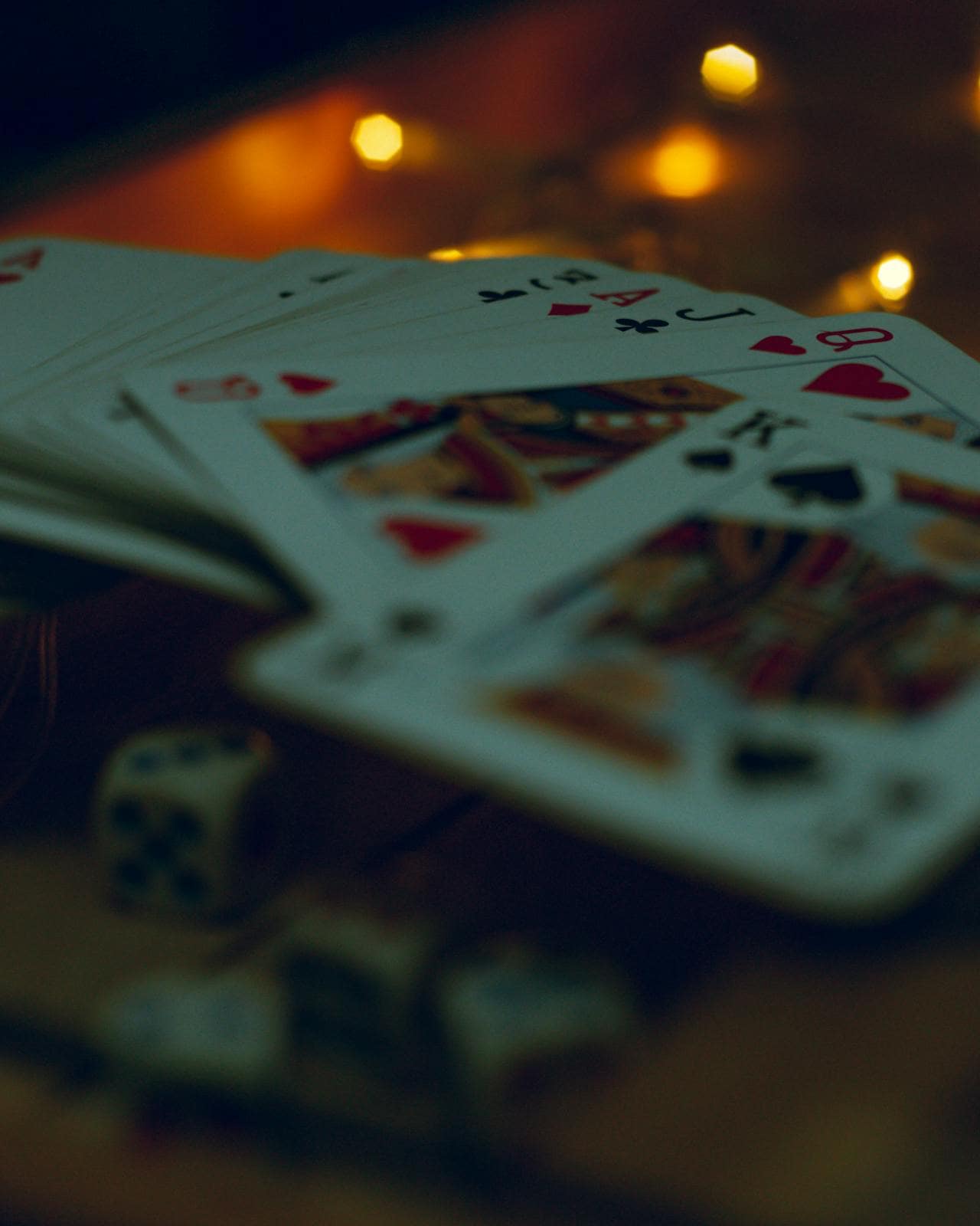 Blurred stack of playing cards and dice on a table, evoking uncertainty and the contrast between human instinct and poker AI strategy.